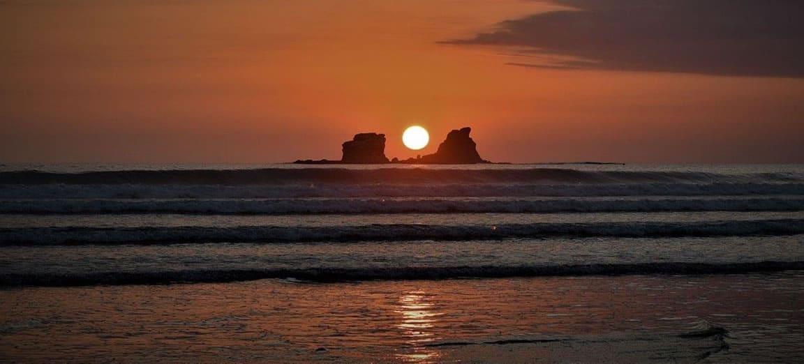 Atardecer en Ayampe, con el sol entre las rocas del islote